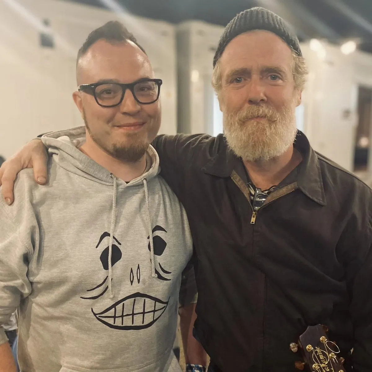 Isaac Birchall standing with Glen Hansard in a record shop, holding a vinyl record.